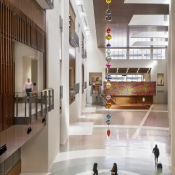 The sculpture is made of a string of colorful glass forms that drop form the atrium ceiling.